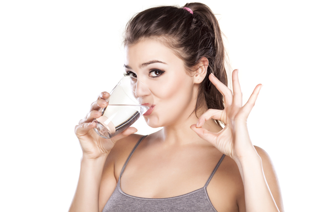 beautiful woman drinks water from a glass and shows delicious